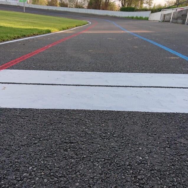 Nahaufnahme einer Rennstrecke mit roten und blauen Linien sowie einer wei&szlig;en Start-/Ziel-Linie im Vordergrund.