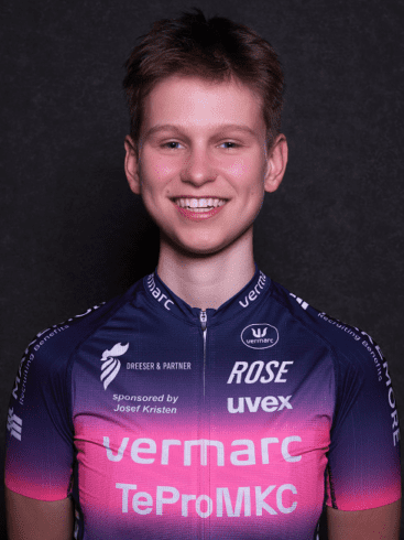 Lächelnder junger Radfahrer in einem bunten Trikot vor schwarzem Hintergrund.