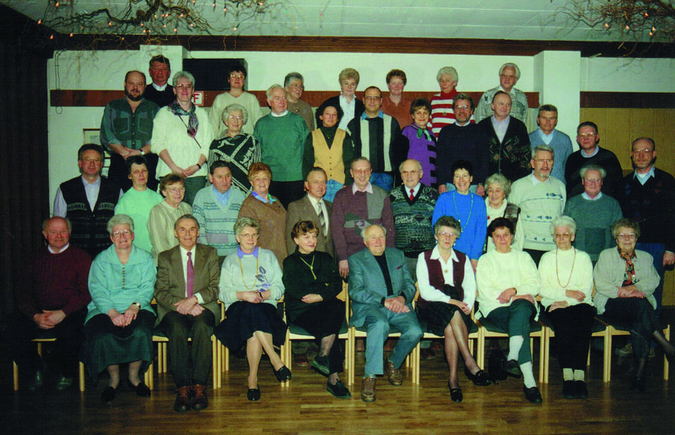 Gruppenfoto von 40 Personen in einem Saal, sitzend und stehend, kleidungsmäßig vielfältig und in fröhlicher Stimmung.
