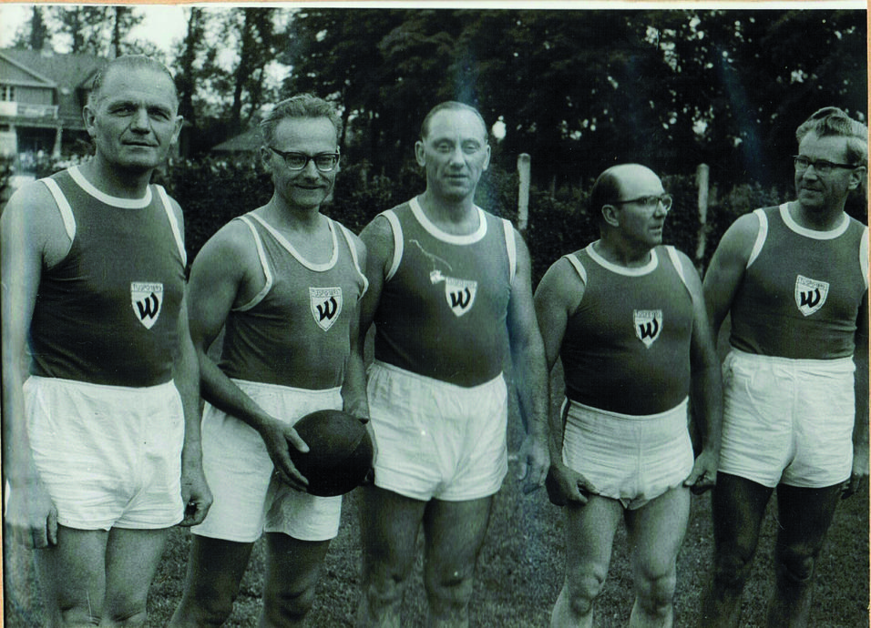Fünf Männer in Sportanzügen stehen mit einem Faustball auf einem Rasenplatz, aufgenommen im Jahr 1962.