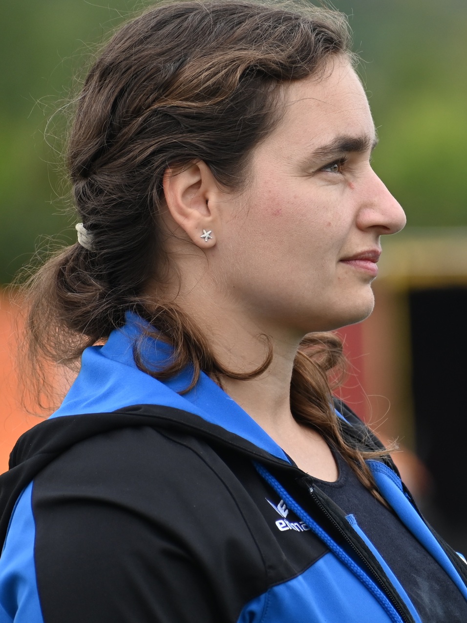 Profilansicht einer Frau mit schulterlangen, braunen Haaren, die einen sportlichen, blauen Hoodie tr&auml;gt.