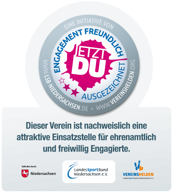 Rundes Logo mit der Aufschrift &bdquo;Jetzt du&ldquo; und den Worten &bdquo;Engagement freundlich ausgezeichnet&ldquo; in pink auf blauem Hintergrund.